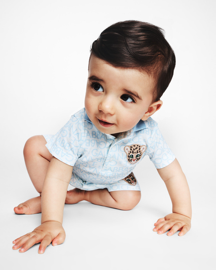 boy wearing baby clothing from kids atelier posing in desert promoting end of season sale 